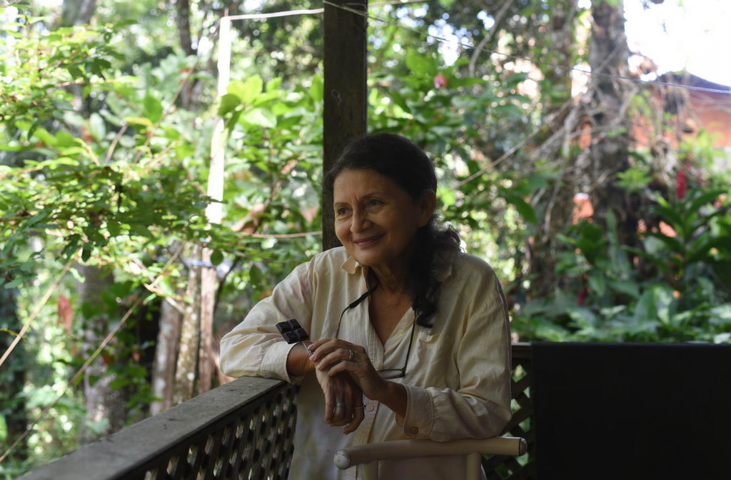 Femme souriante sur une véranda tropicale tenant un carré de chocolat noir.