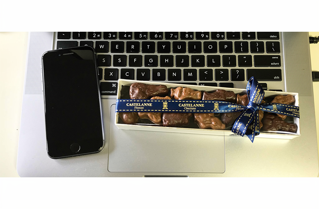 Coffret de chocolats Castelanne avec ruban bleu posé sur un bureau