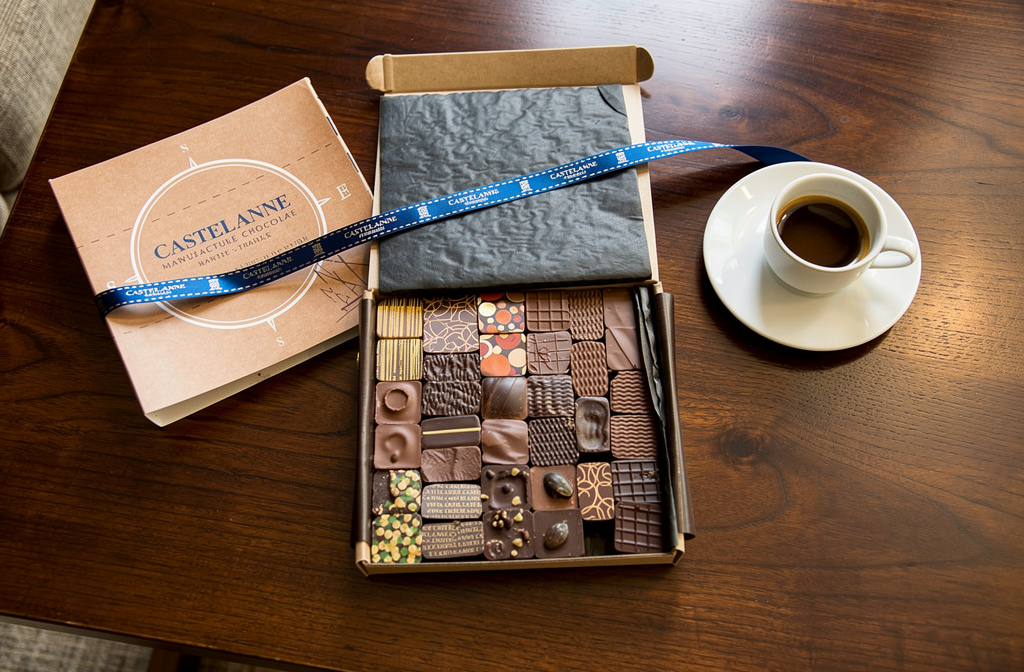 Coffret de chocolats artisanaux Castelanne avec ruban bleu sur une table de salon