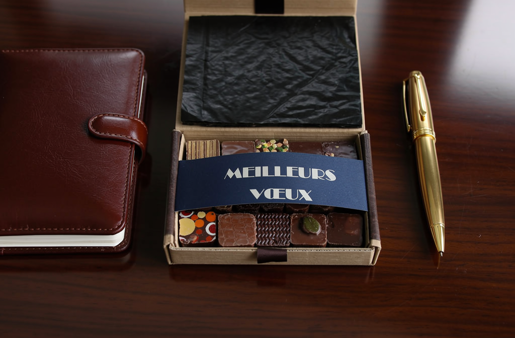 Coffret cadeau de chocolats personnalisés 'Meilleurs Vœux'ouvert sur un bureau d'entreprise élégant