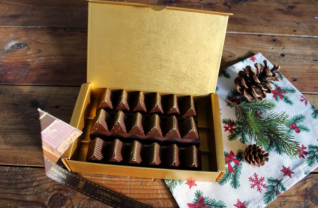Coffret cadeau de chocolats dorés ouvert sur une table de fête de Noël