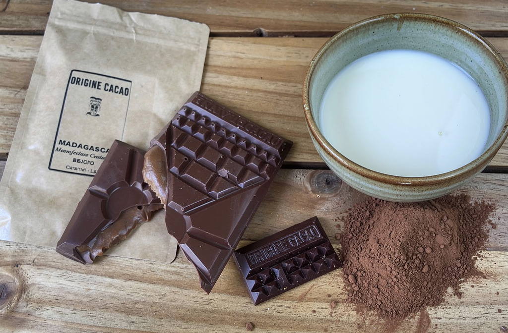 Tablettes de chocolat noir de Madagascar posées sur un plan de travail en bois avec du lait pour préparer du chocolat au lait maison.