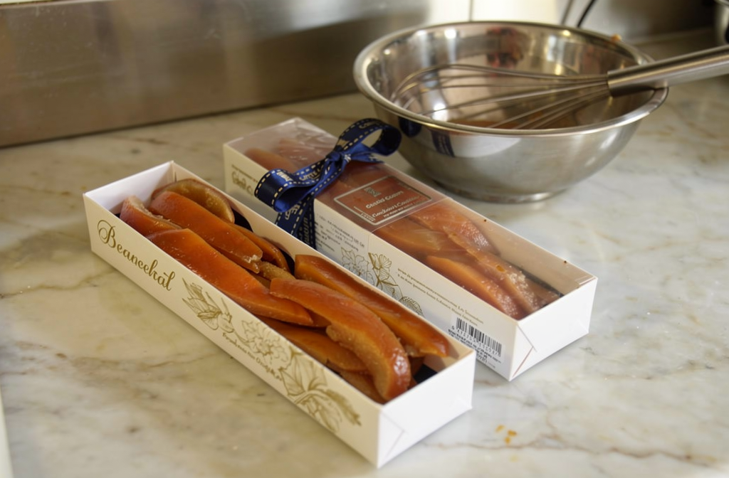 Écorces d'orange confites en boîte cadeau sur un plan de travail de cuisine.