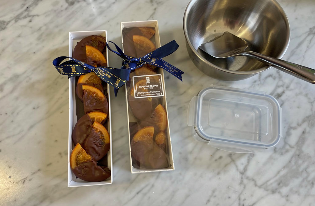 Glaçage miroir au chocolat sur des tranches d'orange confites prêtes à être conservées.