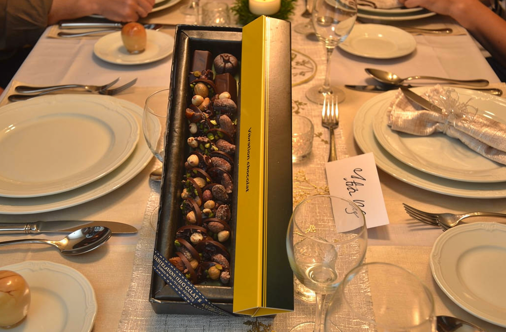 Coffret de chocolats assortis présenté sur une table de fête avec une carte personnalisée