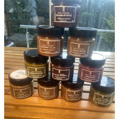 Pâte à tartiner gourmande Castelanne artisanal : pots chocolat noisette disposés en pyramide sur table en bois.