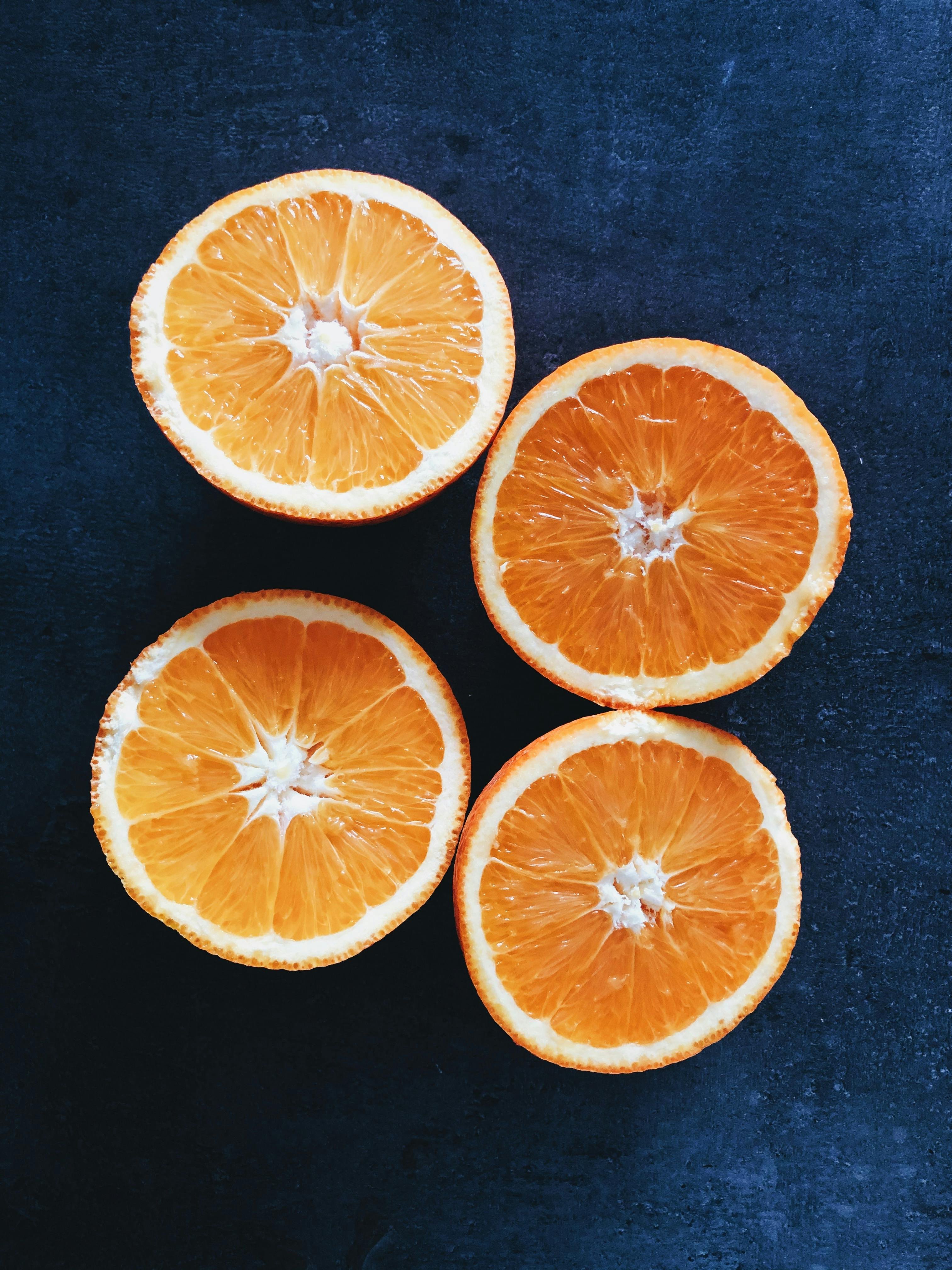 Quartiers d’orange fraîchement tranchés sur fond sombre, couleur vive et textures détaillées.