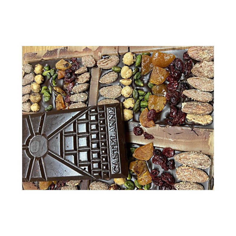 Tablette de chocolat Castelanne entourée de fruits secs et de raisins secs variés, présentation artisanale et gourmande.