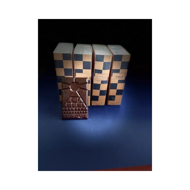 Tablette de chocolat sombre posée devant quatre boîtes à motif damier bleu et beige.